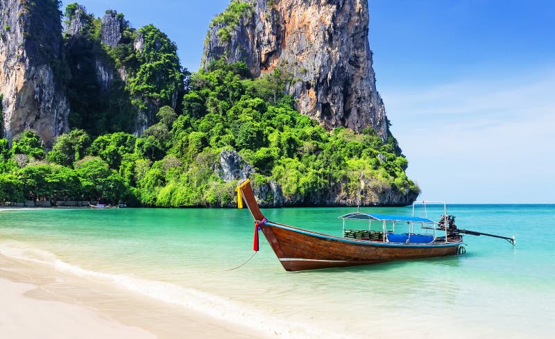 Longtail boat on turquoise water at Railay Beach with limestone cliffs, Krabi