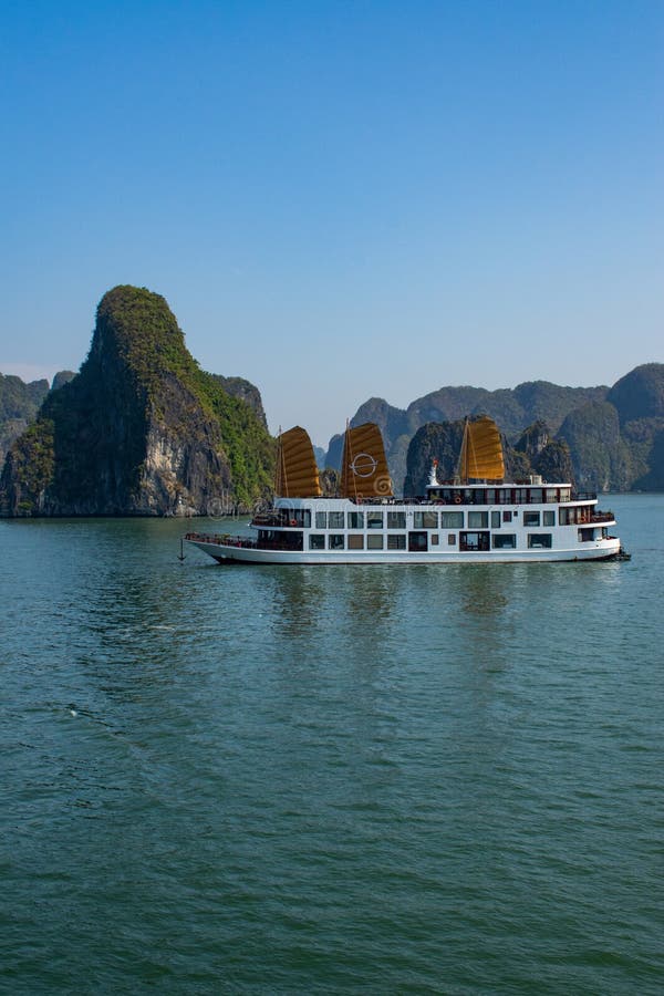 White cruise ship anchored in the green waters of Ha Long Bay