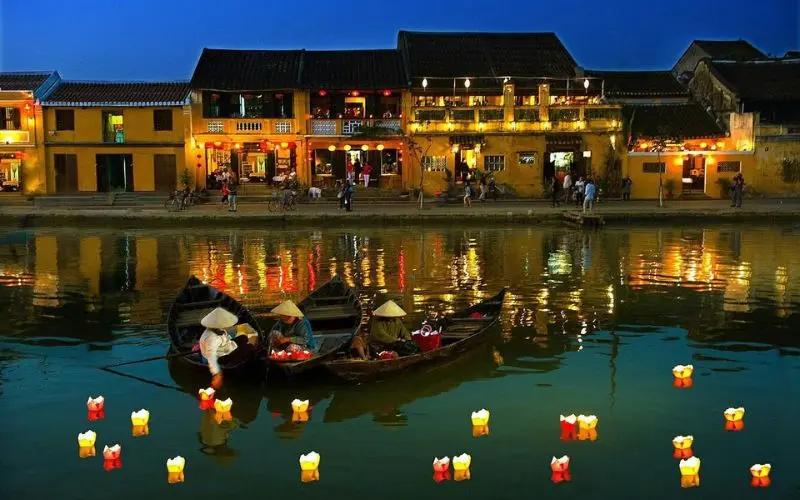Boats and glowing lanterns floating on the river in Hoi An at dusk