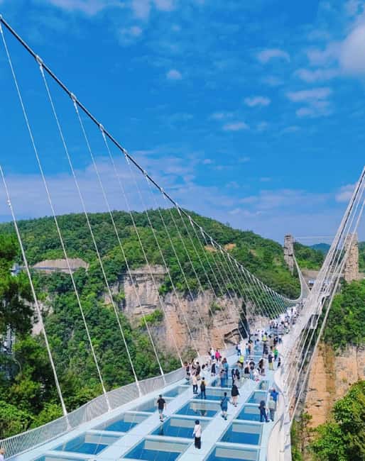 Tourists walking across the glass bridge over Zhangjiajie Grand Canyon